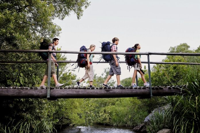Turistas mochileros cruando un puente de madera. 2022 Resumen de la OMT
