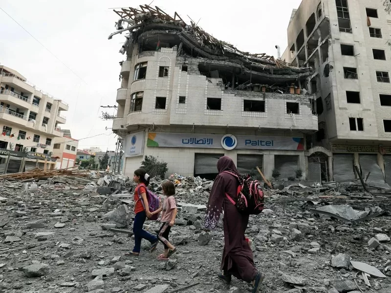 Palestinos caminan entre escombros en medio de la destrucción masiva provocada por los ataques aéreos israelíes en el distrito de al-Rimal de la ciudad de Gaza, el martes 10 de octubre de 2023. Foto propiedad AFP