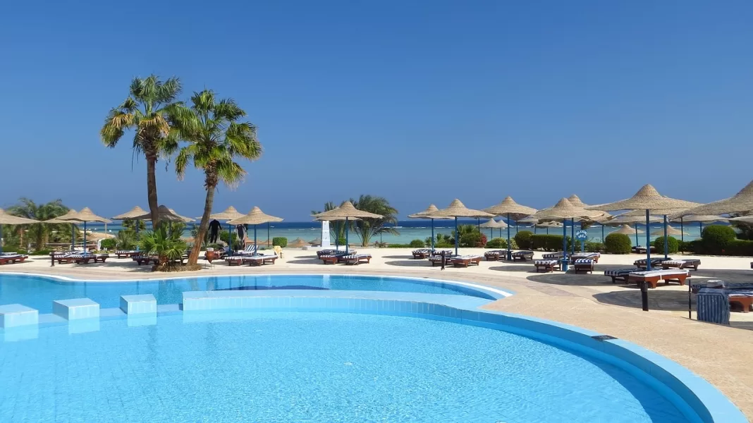 Palmera y piscina y una playa al fondo en un hotel del Caribe