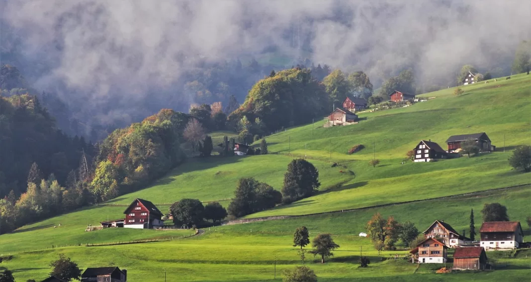 Imagen de un amanecer y casas rurales en los Alpes