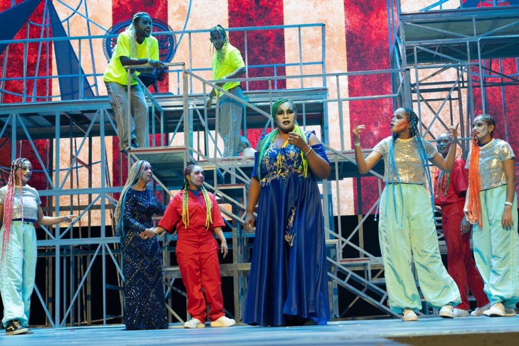 Crítica de teatro: Musical cristiano Dominus LandTiene una notable perfección coreográfica y teatral enfocando la infodemia y su peligro para la unidad familiar que permite volver a escuchar a Claudia Sierra…
José Rafael Sosa
El arte musical cristiano es una caja adorable de sorpresas que, analizado y disfrutado con atención, revela una calidad que debería tener mucho más reconocimiento del que tiene y mucho mayor presencia en las listas de nominaciones a premios
Sus cantantes y agrupaciones constituyen una alta expresión estética, llevando su mensaje de fe y, a nivel del teatro del ámbito nacional, el musical cristiano tiene una tradición establecida por varios proyectos, uno de los cuales es Juventud con una misión RD que acaba de montar Dominus Land en la sala Carlos Piantini del Teatro Nacional Eduardo Brito.
Cuando el espectador llega percibe que está ante un montaje de envergadura y quien sabe si costoso, de lo cual parecen dar una idea los elementos escenográficos: estructuras metálicas y escaleras interconectadas que dan lugar a diversos planos.
Dominus Land vincula el teatro, canto, coreografía, un diseño sobre gran pantalla proyectando imágenes de soporte a la trama en su conjunto. La vitalidad energética de la coreografía, que incluyó ritmos tropicales y urbanos, sobre letras cristianas.
Se hace un excelente uso de tocados de peluquería con las trenzas afro, además de un vestuario impactante, y un maquillaje circense de buen acabado impresionista.
Claudia Sierra, es la voz
El musical nos regala una bendición, escuchar a Claudia Sierra, una contralto cristiana que se dio a conocer en 2016, cuando impactó a los jurados del concurso que desarrolló el programa 7x7 Roberto en Color Visión que ganó arrolladoramente cantando Le llaman Jesús,
Ella hizo en Dominus Land una de las piezas originales y varios solos en el marco de interpretaciones corales. Escucharla evoca momentos de gloria del arte vocal dominicano.,
Aspectos técnicos
Con producción ejecutiva de Omayra Álvarez, quien asumió el reto de montar un trabajo demandante y complejo, apoyada en un imaginativo libreto de la dramaturga, bailarina y coreógrafa Eva Piccini, artista que define un universo de personajes simbólicos con que busca transmitir su mensaje. Es una buena contadora de historias,
Destaca el uso de la tecnología, los envolventes efectos de sonido, el empleo de la pregrabación de los parlamentos, modalidad que ayuda a que lleguen claramente las voces y la música, pero que ya sido superada ya por el uso de micrófonos personales.
Dominus Land sigue la trayectoria de calidad de otros musicales cristianos de esta compañía,: Decido honrarte, El Punto, Dios es el artista, Revelación, La Causa, Red de Sangre y Raíces,
Las actuaciones de Anderson Mercedes (Maestro Sapienta), Eddy Brea Villanova (Asclepio Doupoulus), Amaurys García (Bufón) suman valores artísticamente. En algunos momentos sentimos el vahído de la sobreactuación.
El tema y los patrocinios
El trabajo plantea el peligro de la disolución de las familias haciendo aparecer como un factor responsable a la tecnología, esa que promueve la masificación, el consumismo y el egoísmo, buscando un rescate de la familia. Denuncia la infodemia, exposición excesiva y adictiva de la información digital por las pantallas,
La cuestión es polémica porque incurre en el esquema de lo blanco y lo negro, asumiendo que la tecnología es mala en sí misma, cuando es solo un medio que se puede usar bien o usar mal.
De hecho, el mismo montaje musical, emplea sabiamente la tecnología y la Inteligencia Artificial, desde la gran pantalla del fondo. Pero es un tema para debatir infinitamente sin llegar a acuerdo.
Dominus Land fue patrocinado por Rental Visión, Printeo, el enlace del Gobierno Dominicano con las Iglesias Cristianas, Luis Betances, Sinai P&P, el Consejo Dominicano de Unidad Evangélica (CODUE), el proyecto Enfocado en la Gran Comisión, la Mesa de Diálogo y Representación Cristiana y la empresa cinematográfica Caribbean Cinemas.
Ficha Técnica
Título: Dominus Land
Género: Teatro Musical
Producción ejecutiva: Omayra Álvarez
Libreto y dirección teatral y coreográfica: Eva Piccini
Dirección técnica: Juventud con una Misión JUCUM Santo Domingo.
Escenografía: Tacke Stage (Ángela Bernal)
Musicalización: Eddy Francis Brea
Línea gráfica: Estephany Mesa Méndez
Videografía: Annette Heredia y Loammy Torres
Elenco principal: Eva Piccini, Claudio Sierra, Anderson Mercedes (Maestro Sapienta), Eddy Brea Villanova (Asclepio Doupoulus). Amaurys García (Bufón).
Sinopsis
La isla Dominus Land, gobernada por el malvado Asclepio Doupoulus, en la cual padres cruelmente separados de sus hijos y que son obligados a servir como cirqueros, pese a lo cual no aceptan ese destino y se rebelan para recuperar sus familias y lograr sea gobernada por el Maestro Sapienta, un líder de bondad y amor.
Pie de foto
Escena de Dominus Land, musical cristiano que llevó su mensaje de unidad y rescate familiar, presentado en el Teatro Nacional Eduardo Brito.