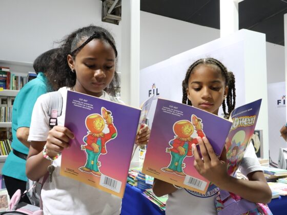 Dos j&oacute;venes estudiantes ojean obras literarias durante una visita a la Feria.
