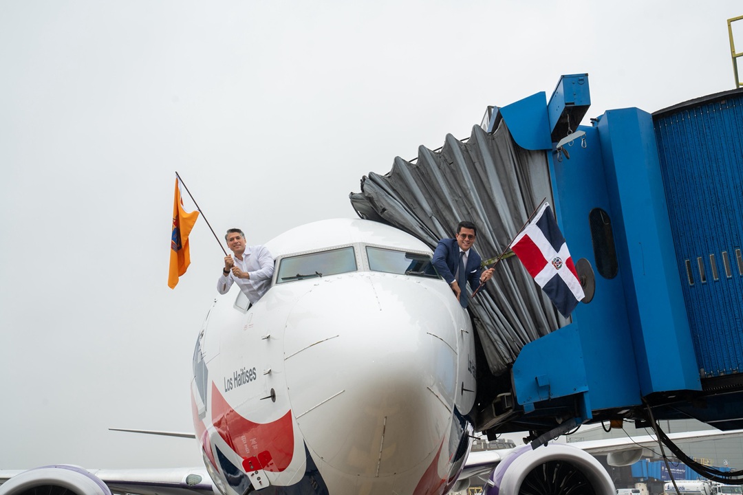 David Collado y Víctor Pacheco ondean banderas desde la cabina del avión de Arajet al llegar a Nueva York