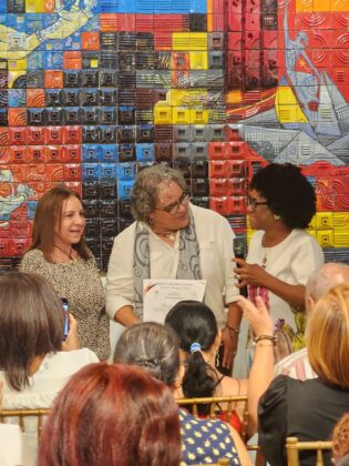 lonka V&aacute;squez recibe su certificado de reconocimiento entregado por Ana Mar&iacute;a Henr&iacute;quez y Altagracia Mella Russo.